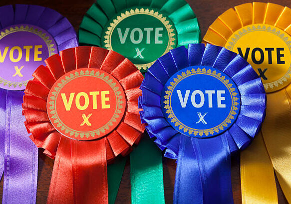Voting in a UK Election. Coloured Rosettes for the principal UK political parties